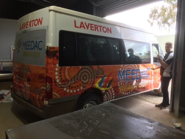 A man is standing next to a colorful van in a garage.