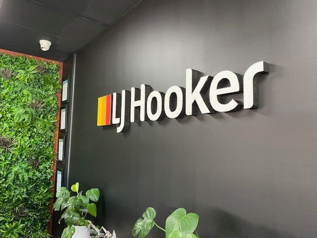 The word hooker is on a black wall next to a plant.