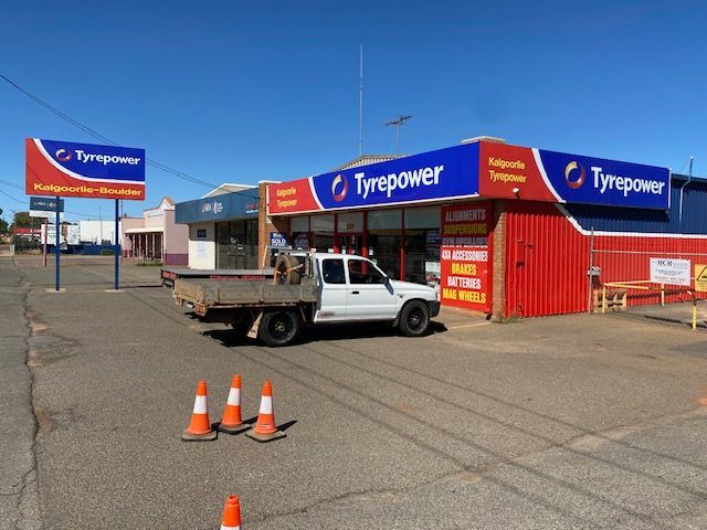 A white truck is parked in front of a tyrepower store