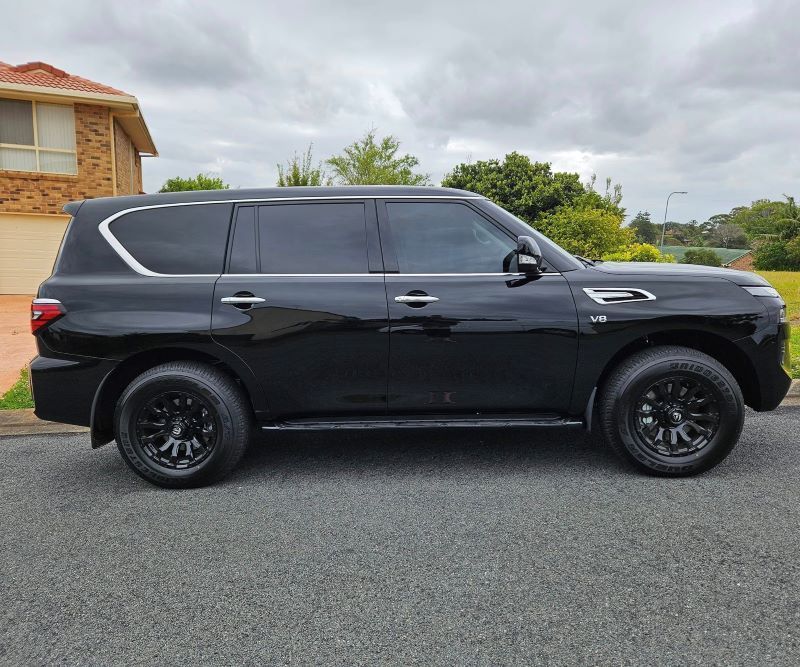 A Black Suv is Parked on the Side of the Road in Front of a House — PJ Tinting In Laurieton, NSW