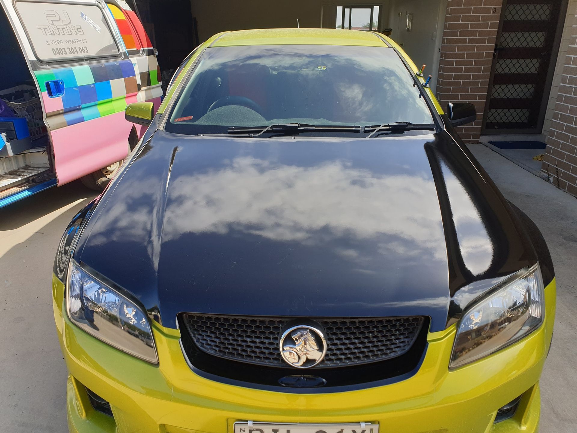 A Gray Car is Parked in a Gravel Lot in Front of a Fence — PJ Tinting In Port Macquarie, NSW