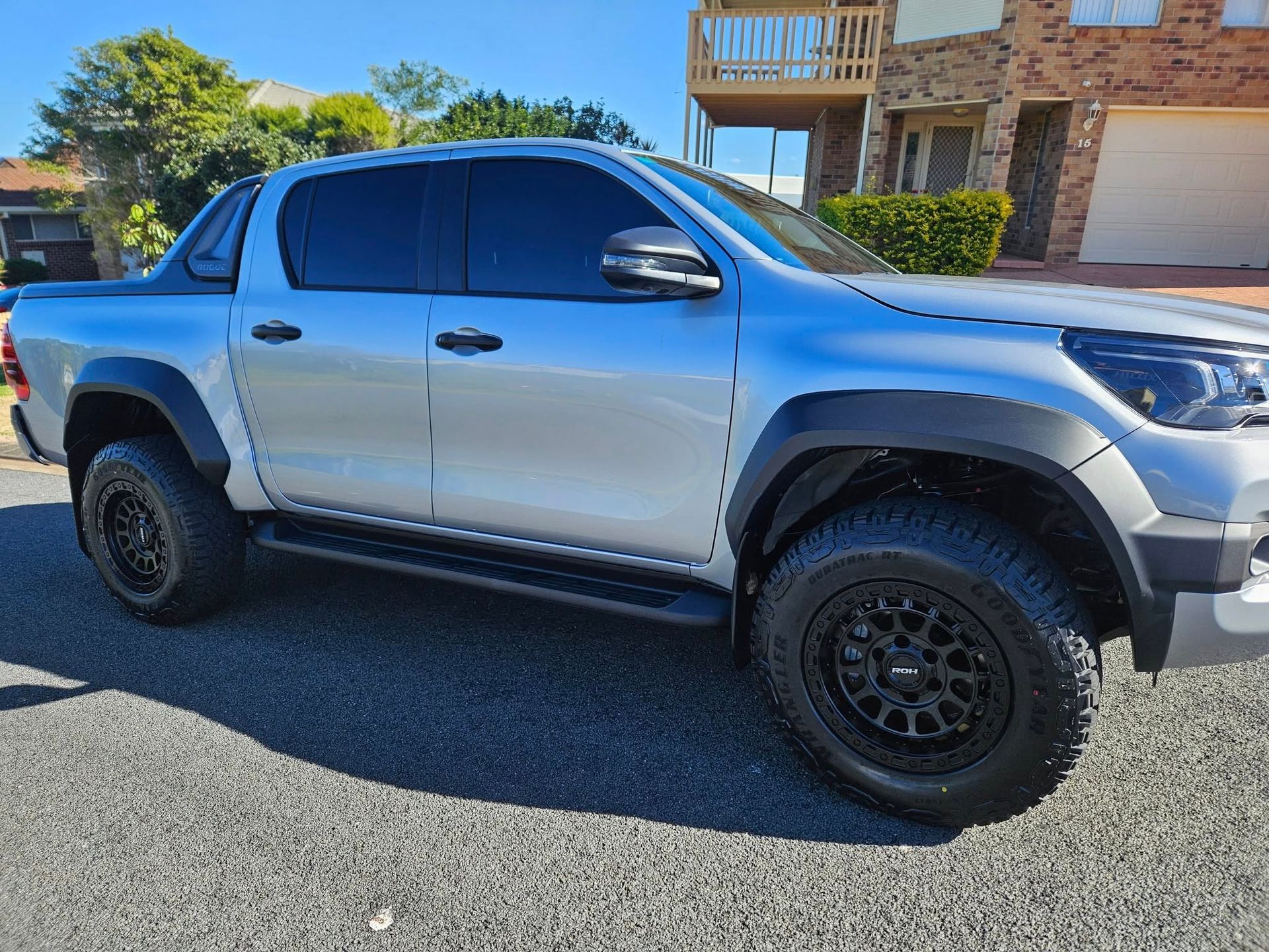 Silver pickup truck parked on a street; black wheels and tinted windows.