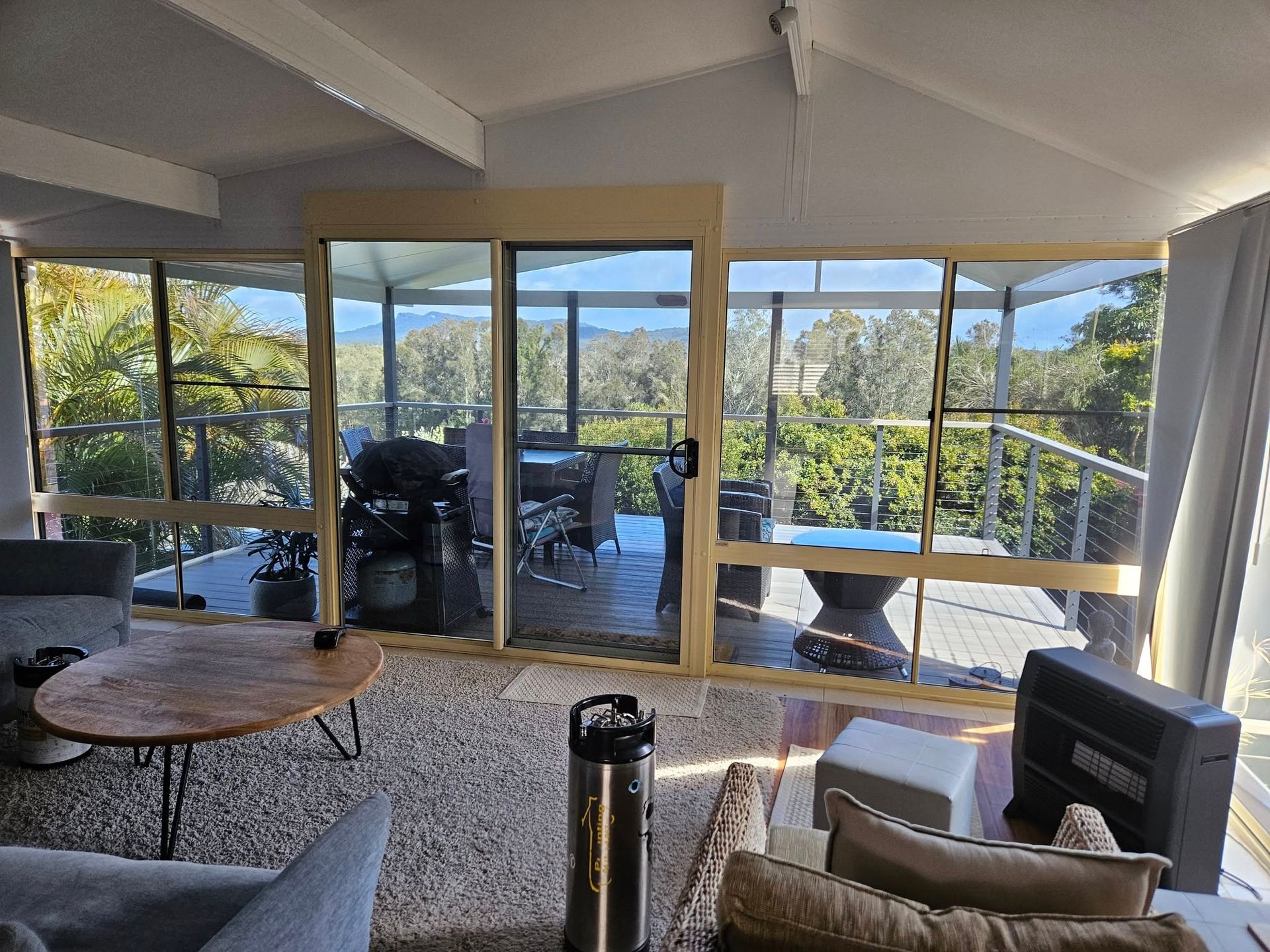 Living room with sliding glass doors opening to a deck overlooking a green landscape.