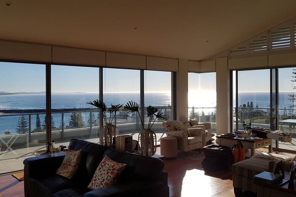 A Living Room With a Couch and Chairs and a View of the Ocean — PJ Tinting In Port Macquarie, NSW