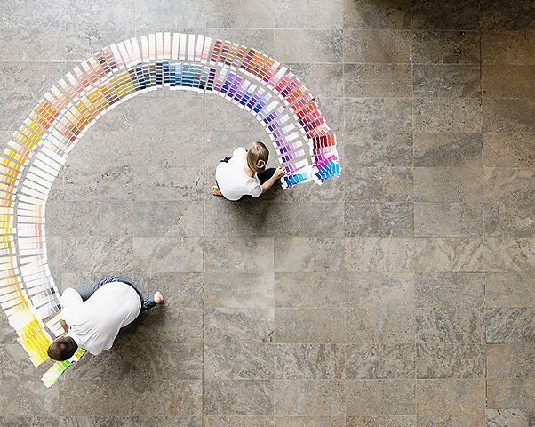 Two people are looking at a rainbow of paint samples on the floor.