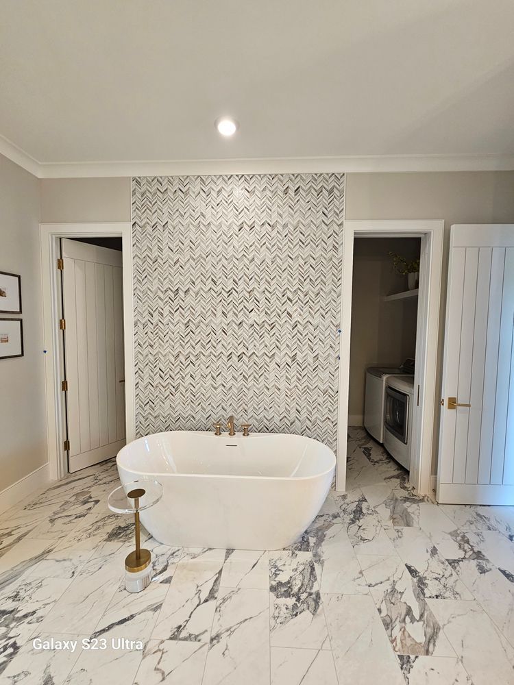A bathroom with a bathtub and a marble floor.