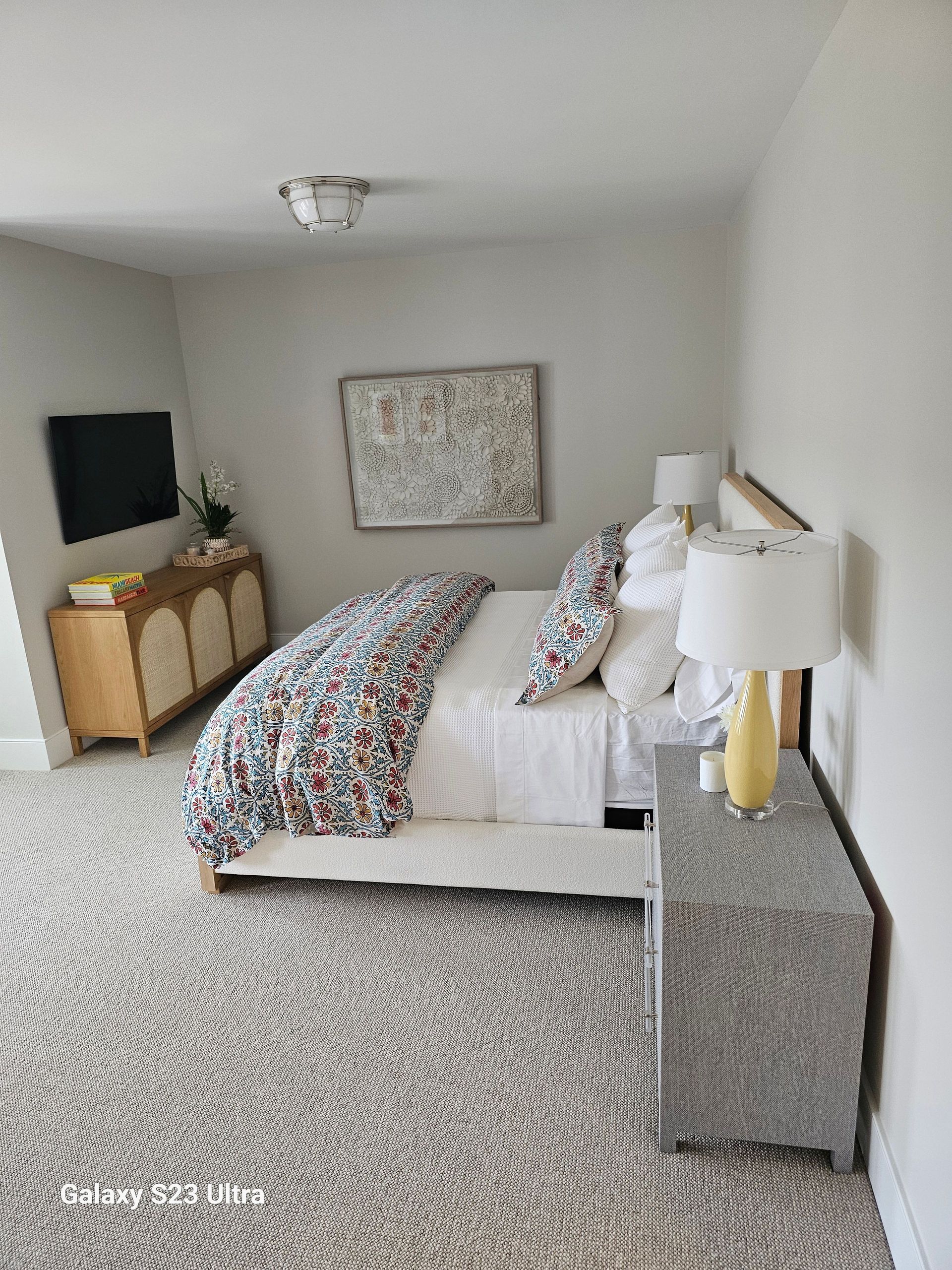 A bedroom with a bed , nightstand , lamps and a television.