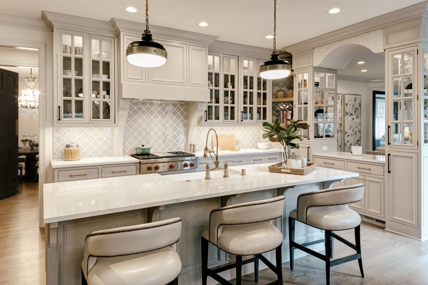 A kitchen with white cabinets , a large island , and stools.