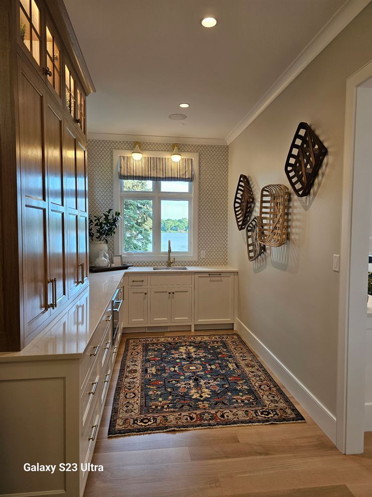 A long hallway leading to a kitchen with a rug on the floor.