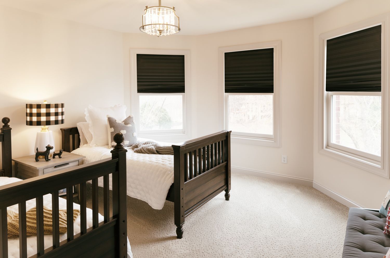 A bedroom with two beds , two windows and black blinds.