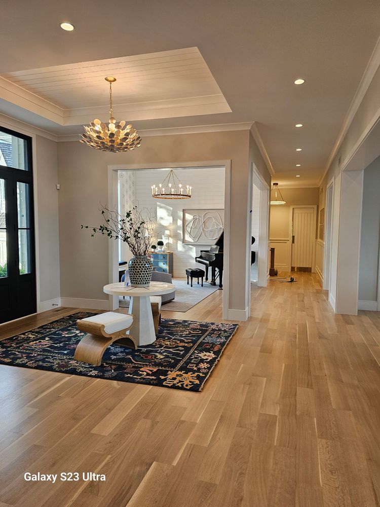 A hallway in a house with hardwood floors and a chandelier.