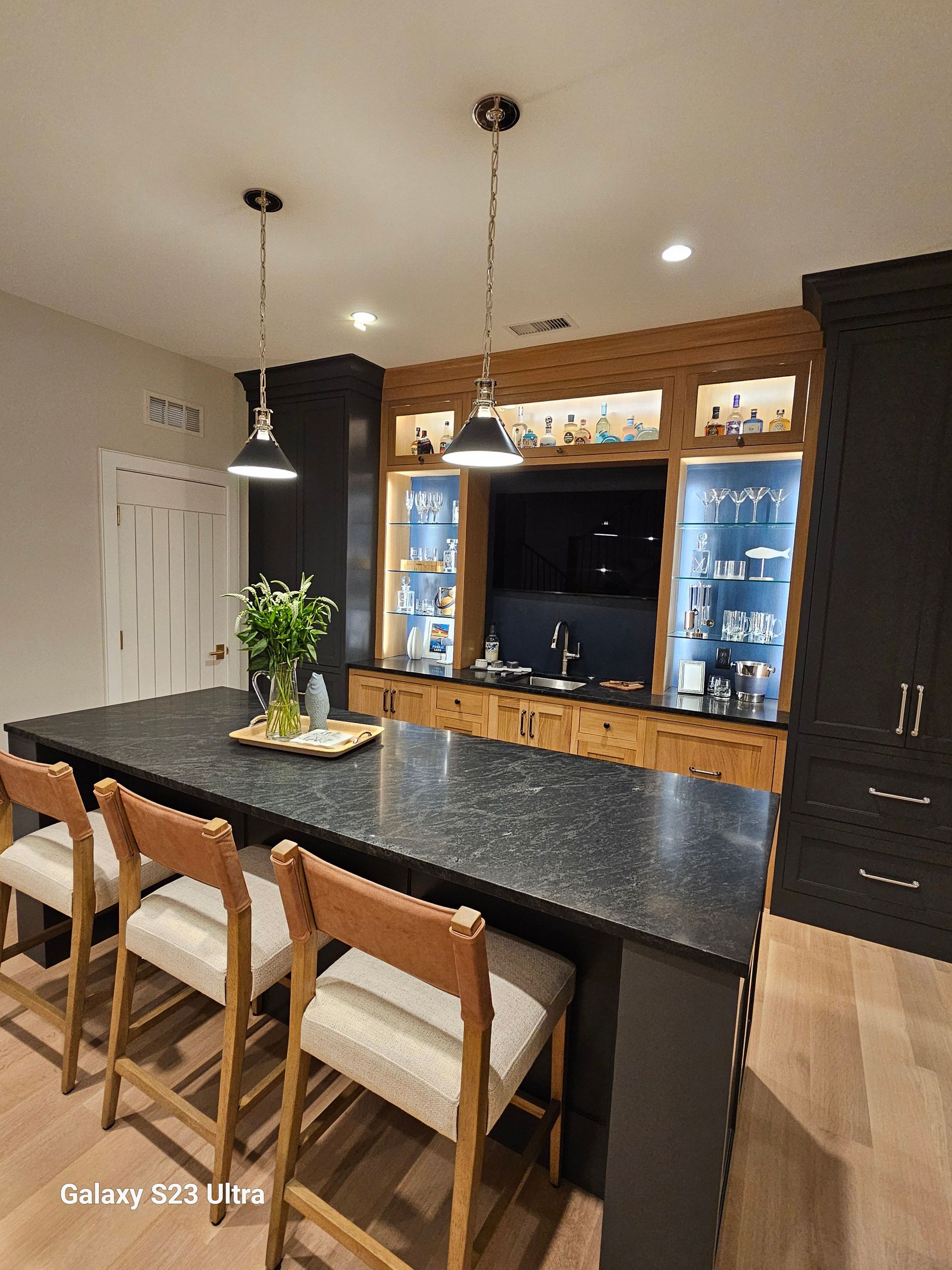 A kitchen with a large island and chairs in it.