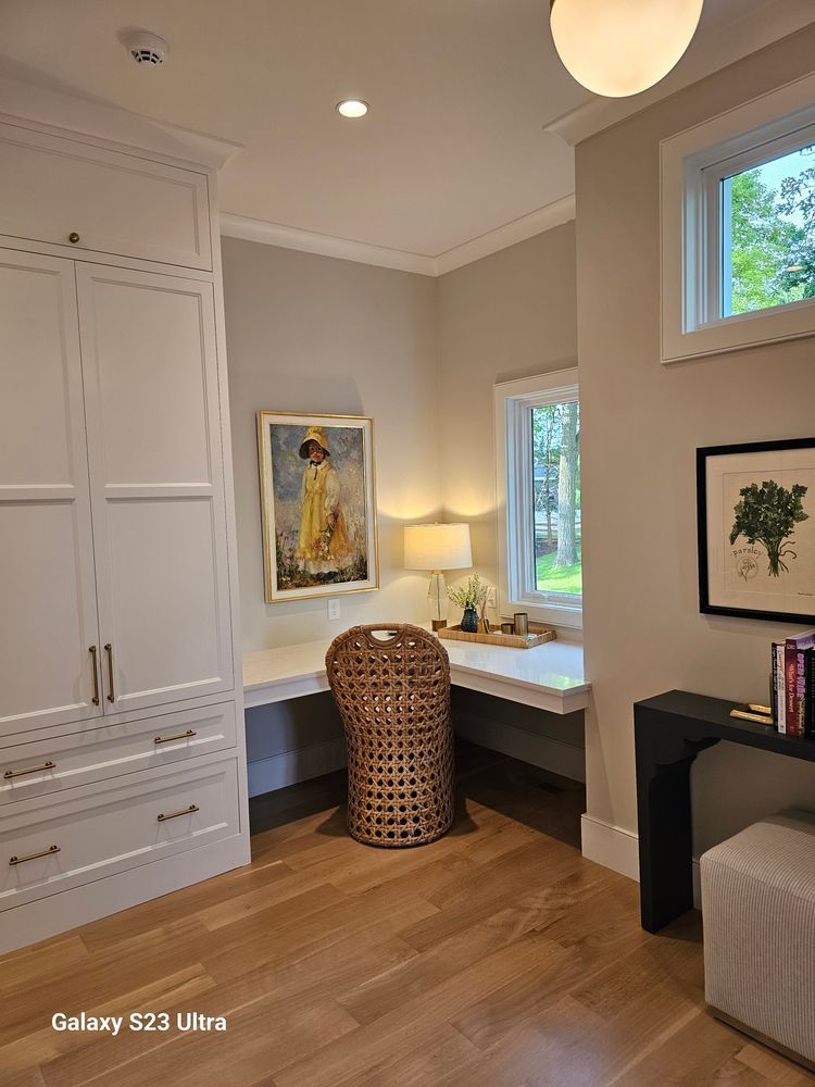 A room with a desk , chair and a painting on the wall.