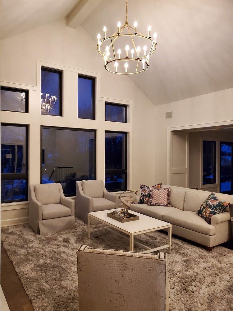 A living room with a couch , chairs , a coffee table and a chandelier.