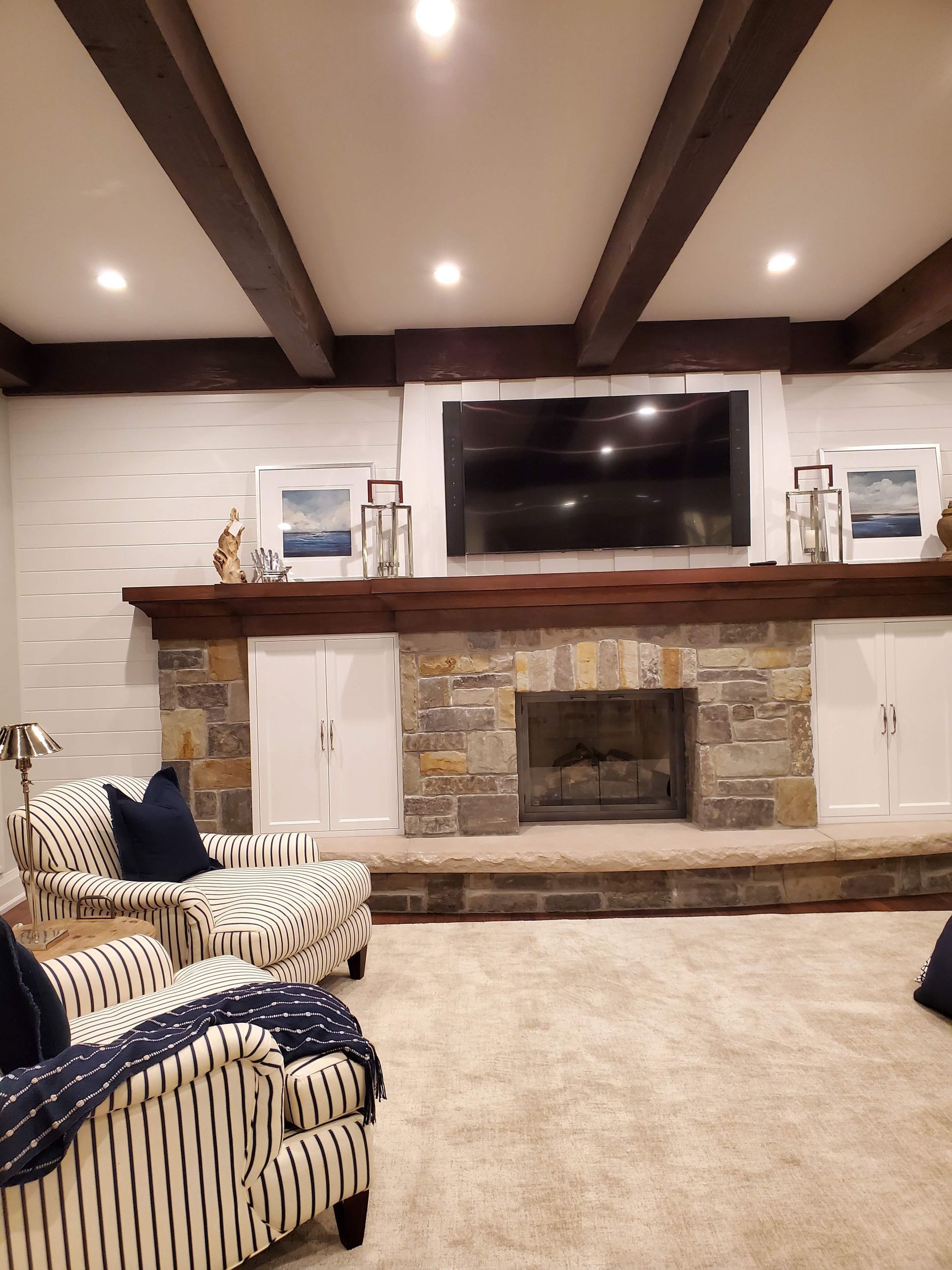 A living room with a fireplace , chairs , and a flat screen tv.