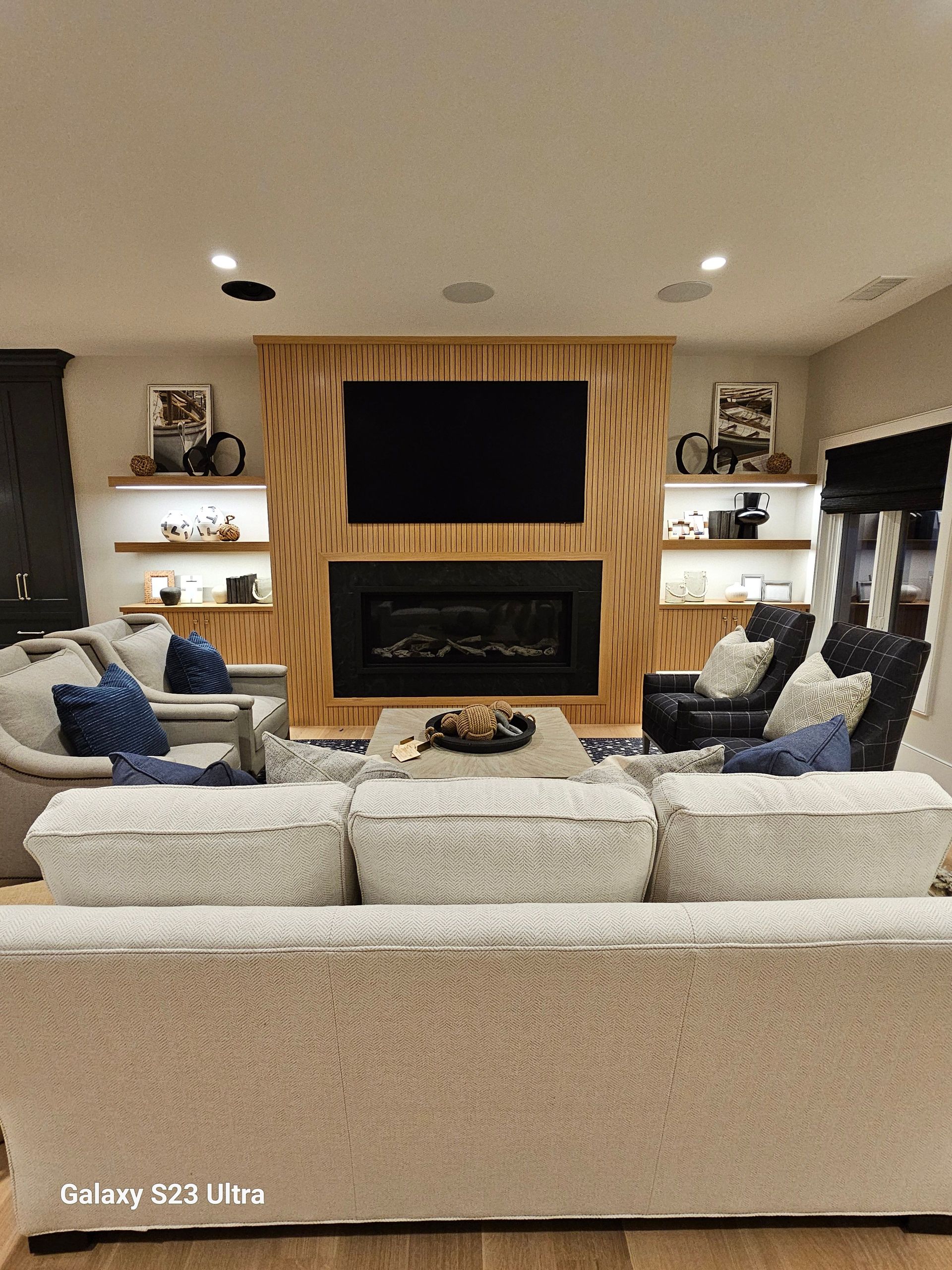 A living room with a couch , chairs , a fireplace and a flat screen tv.