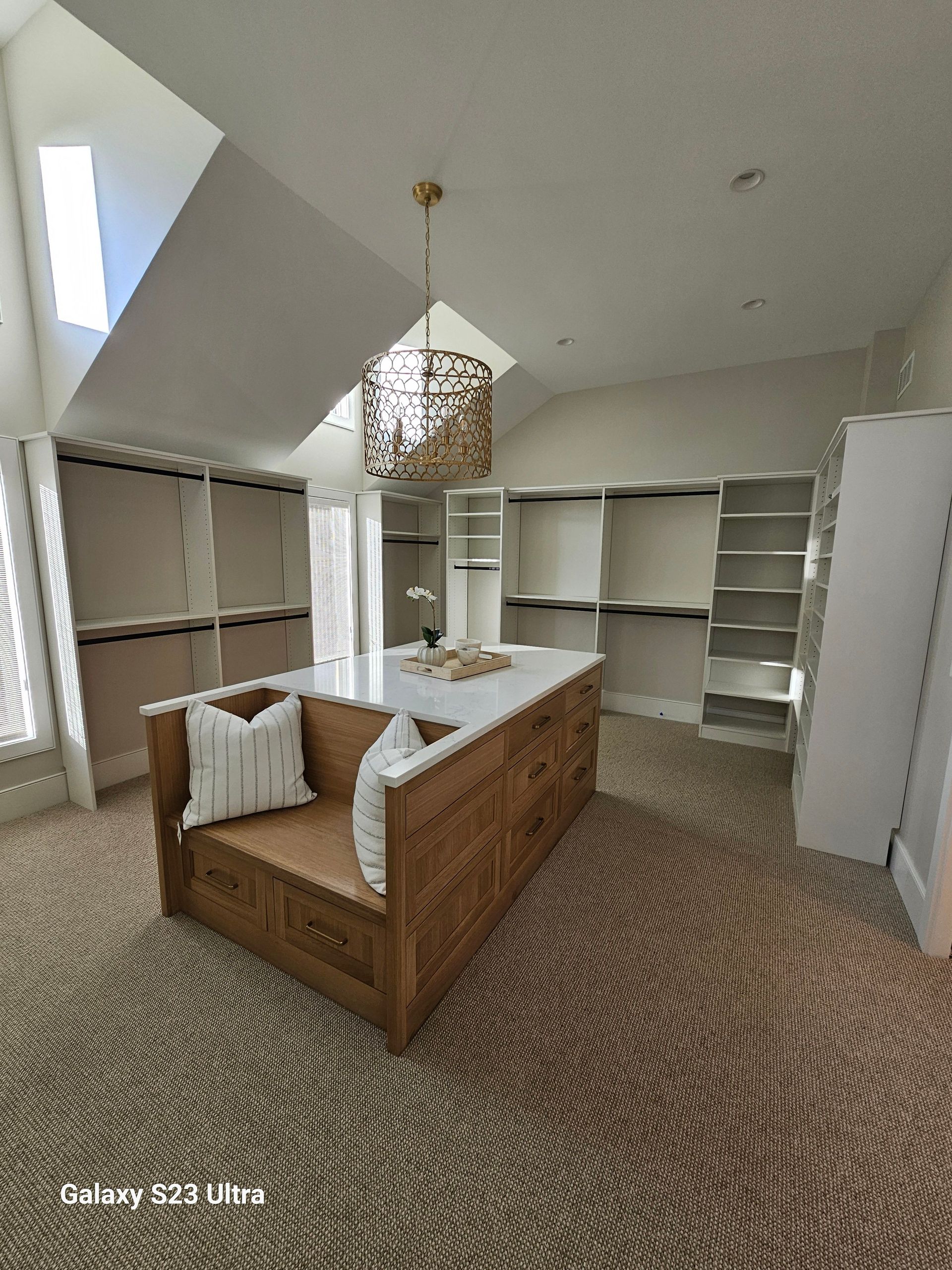 A walk in closet with a large island in the middle of it.