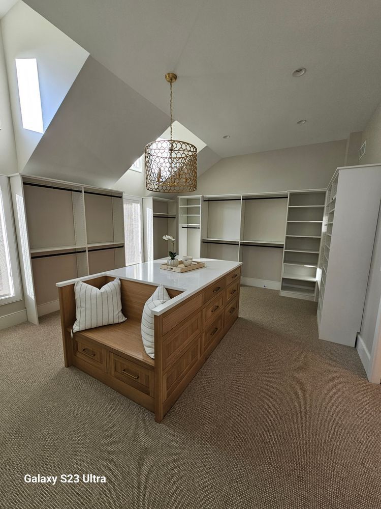 A walk in closet with a large island in the middle of it.