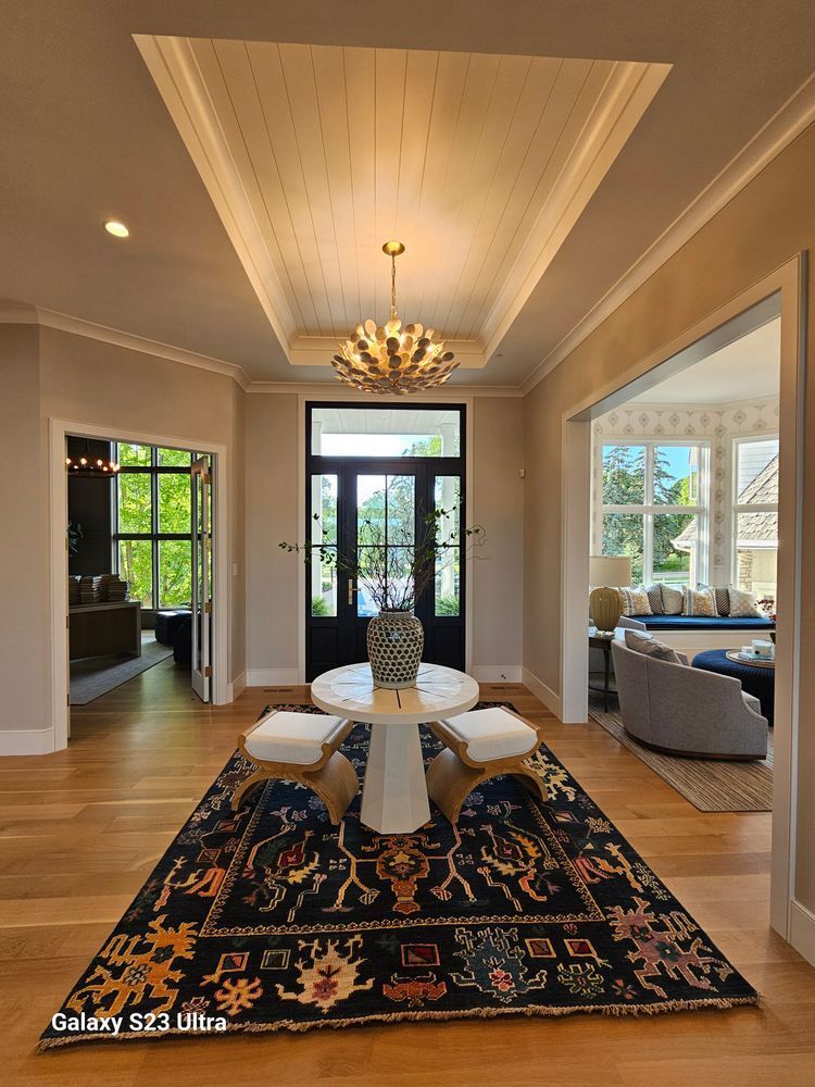 A living room with a rug on the floor and a chandelier hanging from the ceiling.