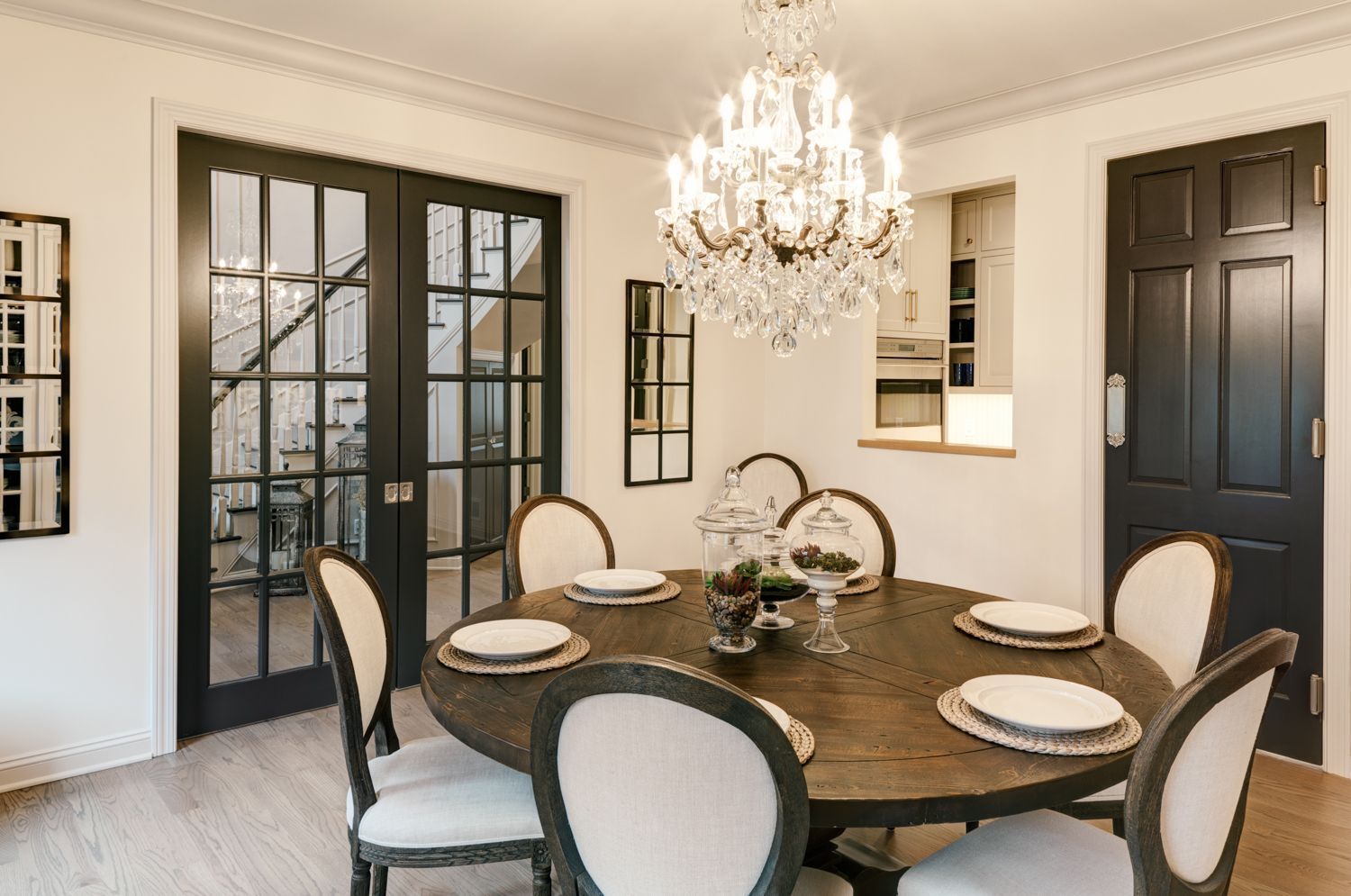 A dining room with a round table and chairs and a chandelier.