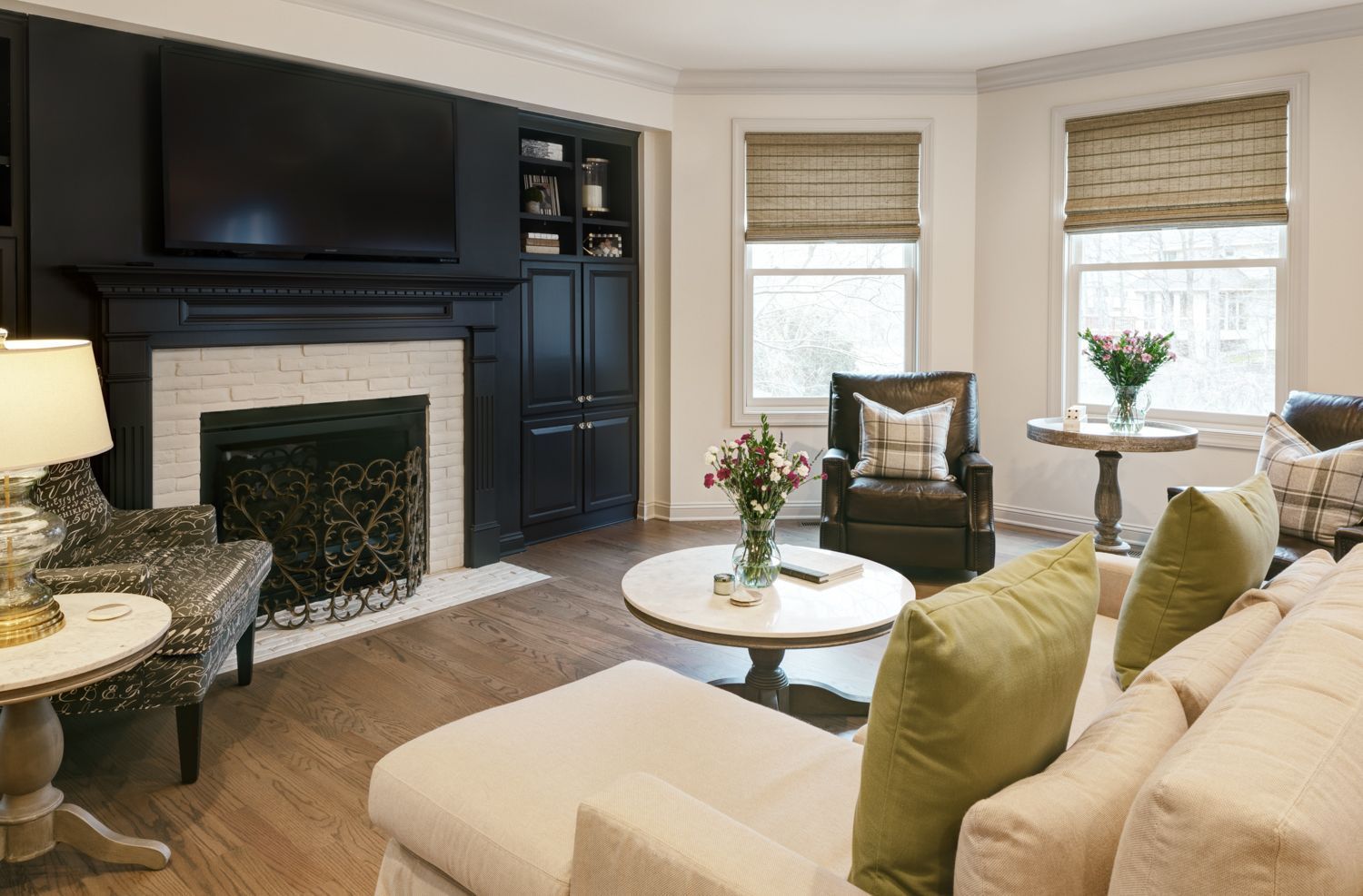 A living room with a fireplace , couch , chairs , table and television.