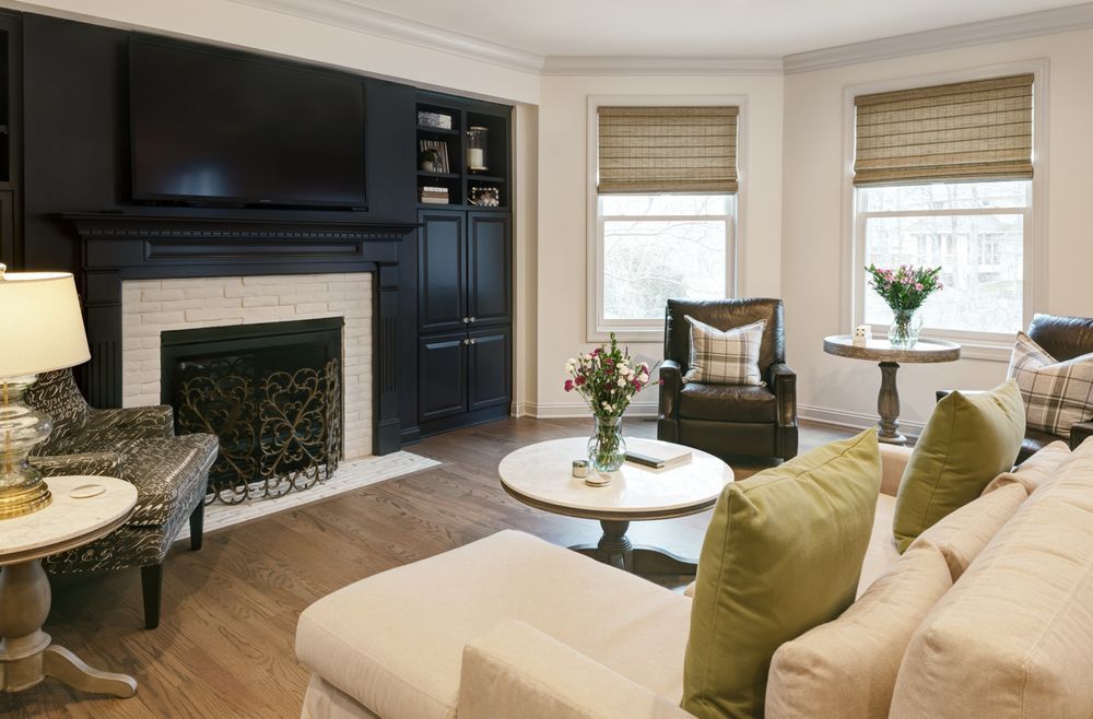 A living room with a fireplace , couch , chairs , table and television.