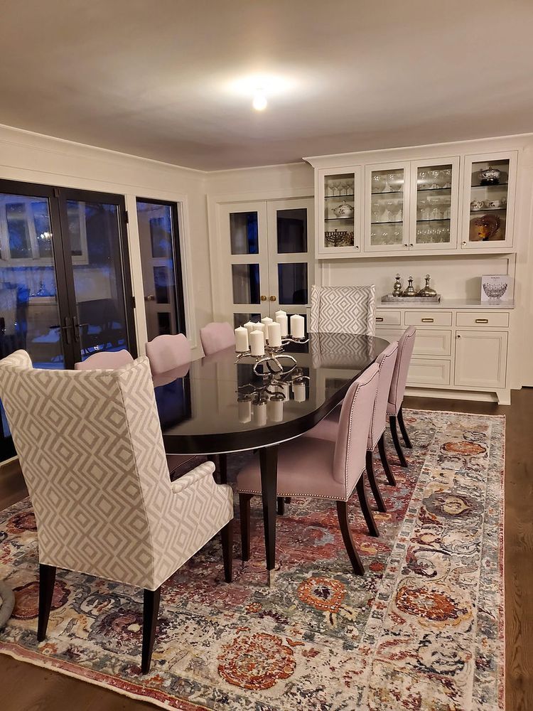 A dining room with a table and chairs and a rug.