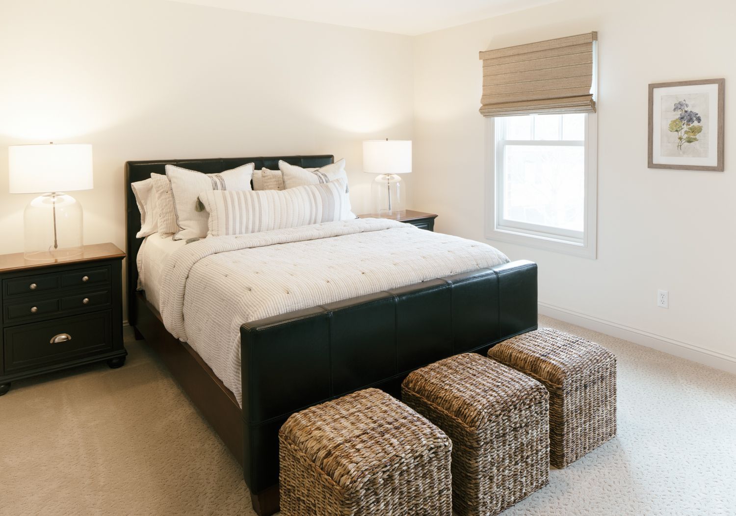 A bedroom with a king size bed and wicker ottomans