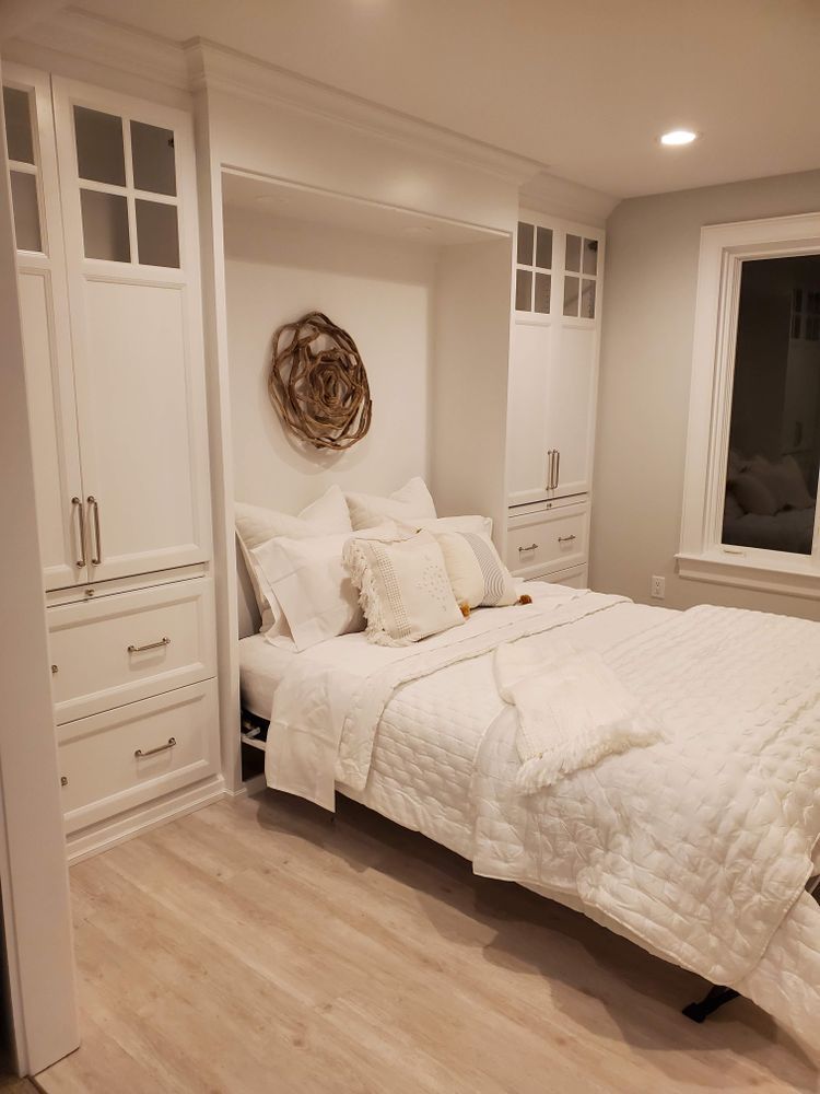 A bedroom with a bed , cabinets , drawers and a window.