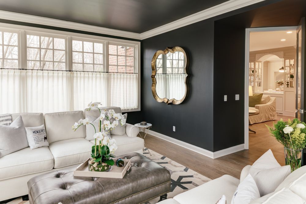 A living room with a couch , ottoman , coffee table and mirror.