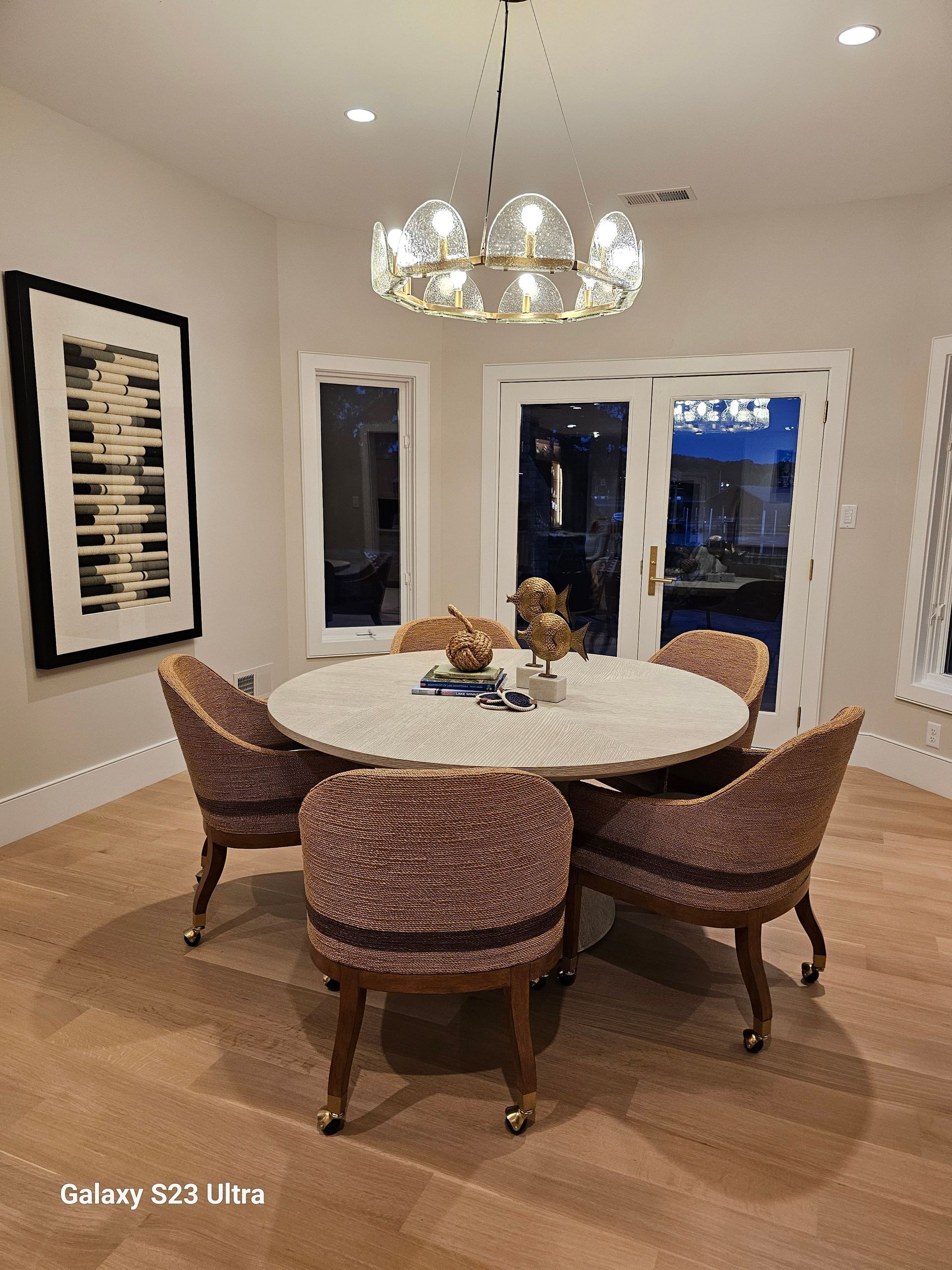 A dining room with a round table and chairs and a chandelier.