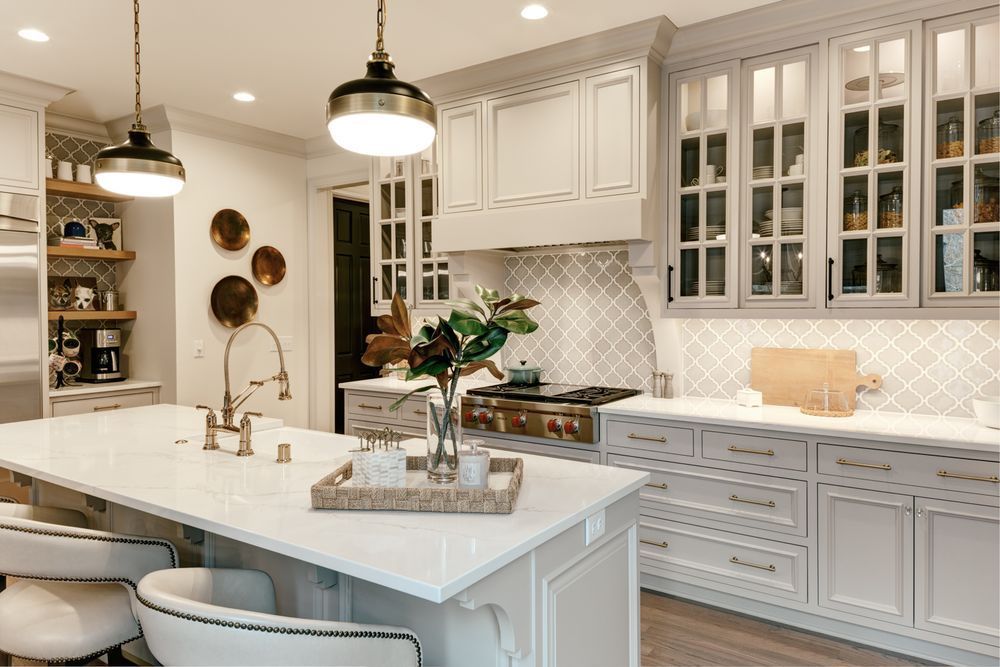 A kitchen with white cabinets , white counter tops , and a large island.