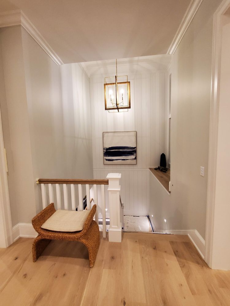 A hallway with a staircase and a chair in the middle of it.