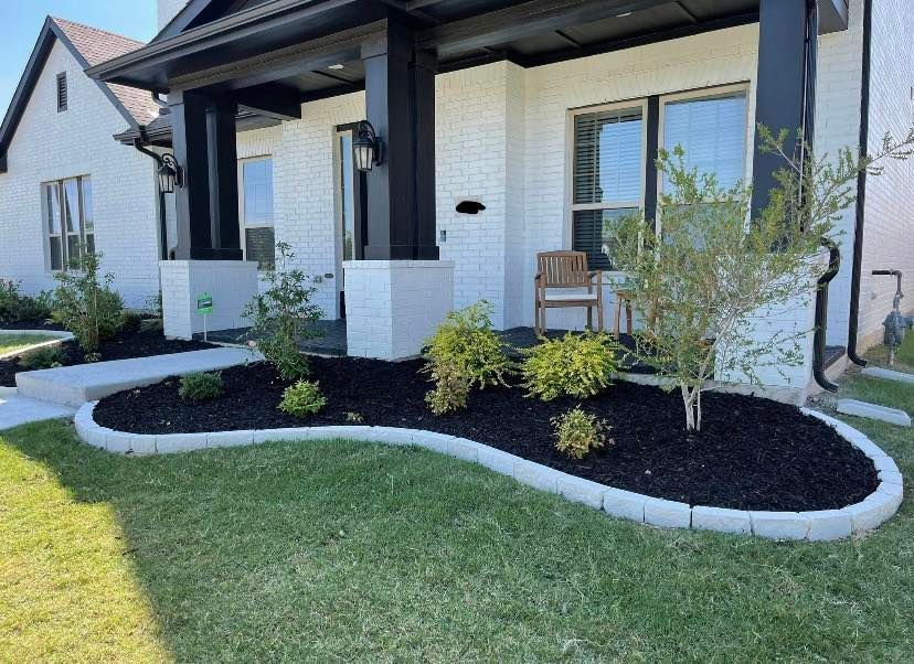Front of a modern brick house with dark mulch landscaping and a curving concrete border.