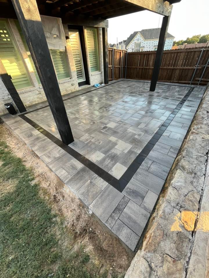 Newly paved patio with gray and black rectangular pavers, under a covered structure.