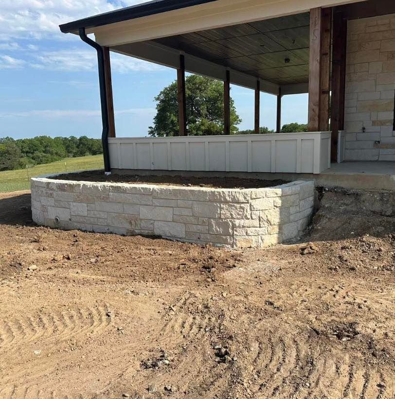 Stone retaining wall in front of a porch with a covered patio.