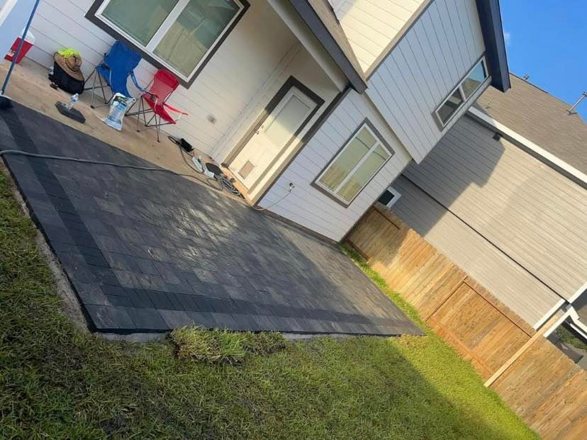 Backyard with a black rectangular patio rug, green grass, and a two-story house.