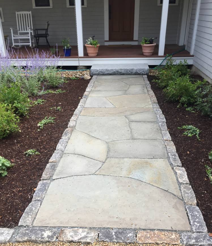 Stone walkway leading to a front porch with landscaping and potted plants.