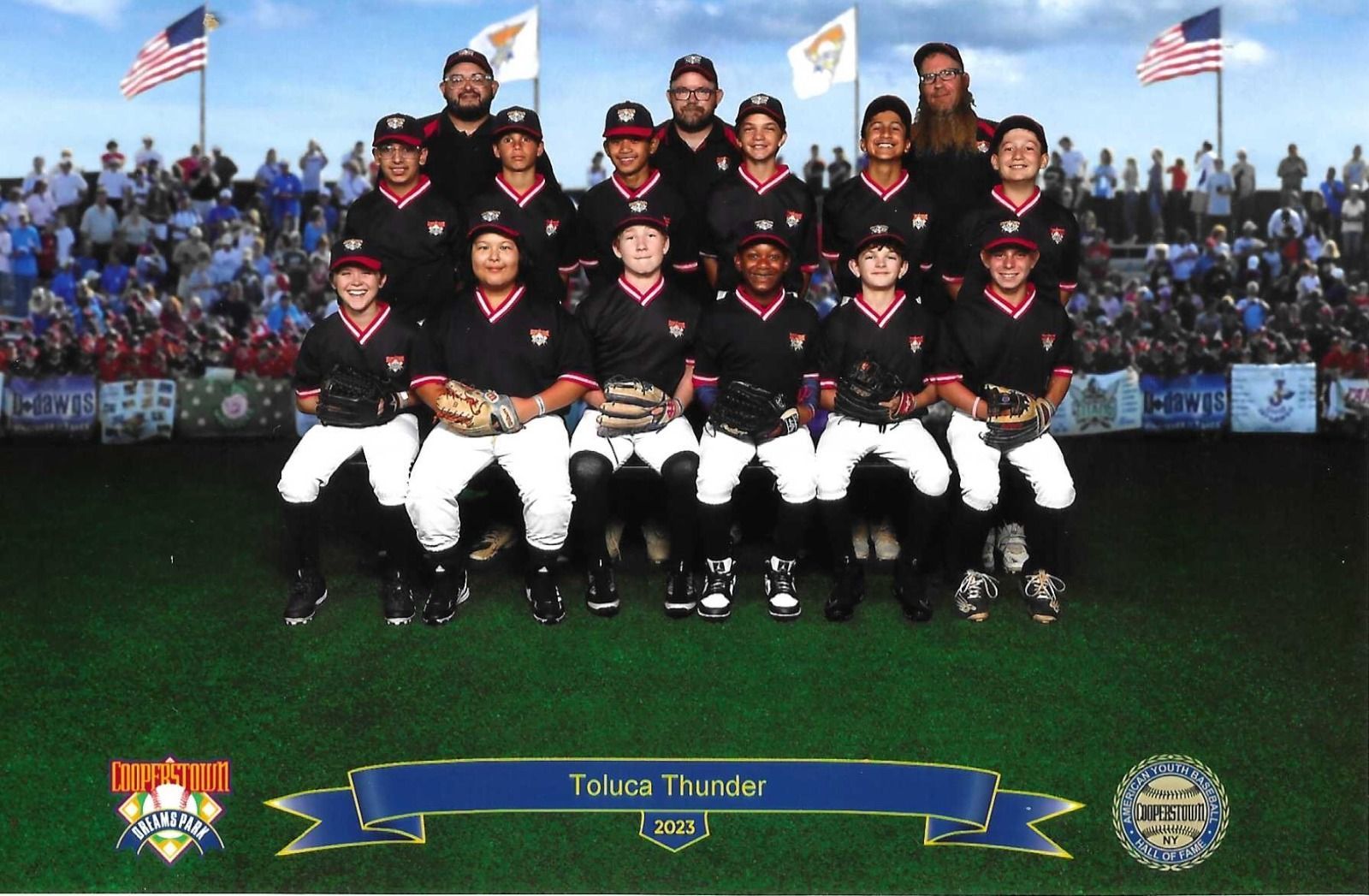 Baseball team, Texas Thunder, posing on a field. Players in black uniforms, white pants. Coaches in back, spectators in background.