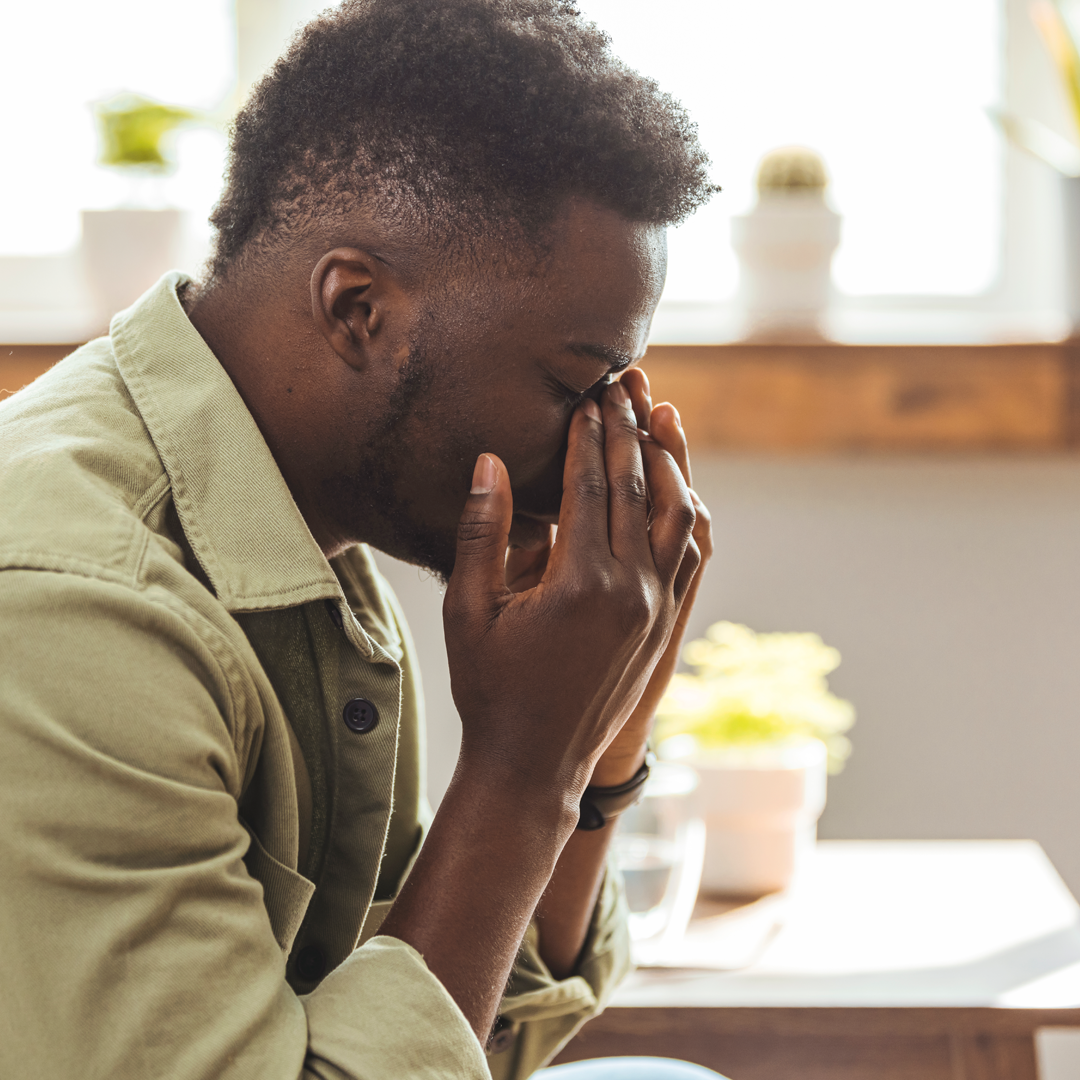 A man is sitting at a table with his hands on his face.