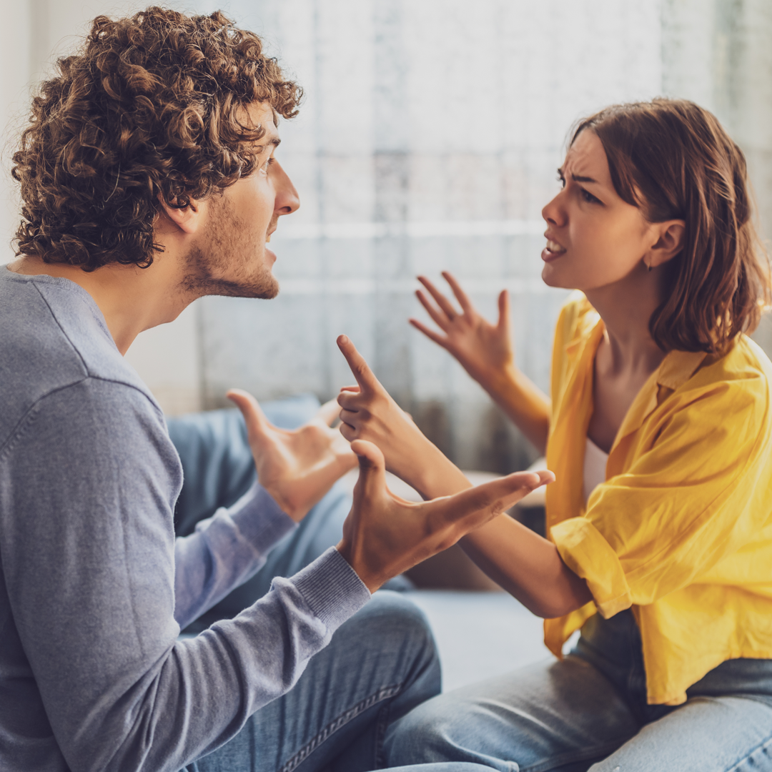 A man and a woman are sitting on a couch having an argument.