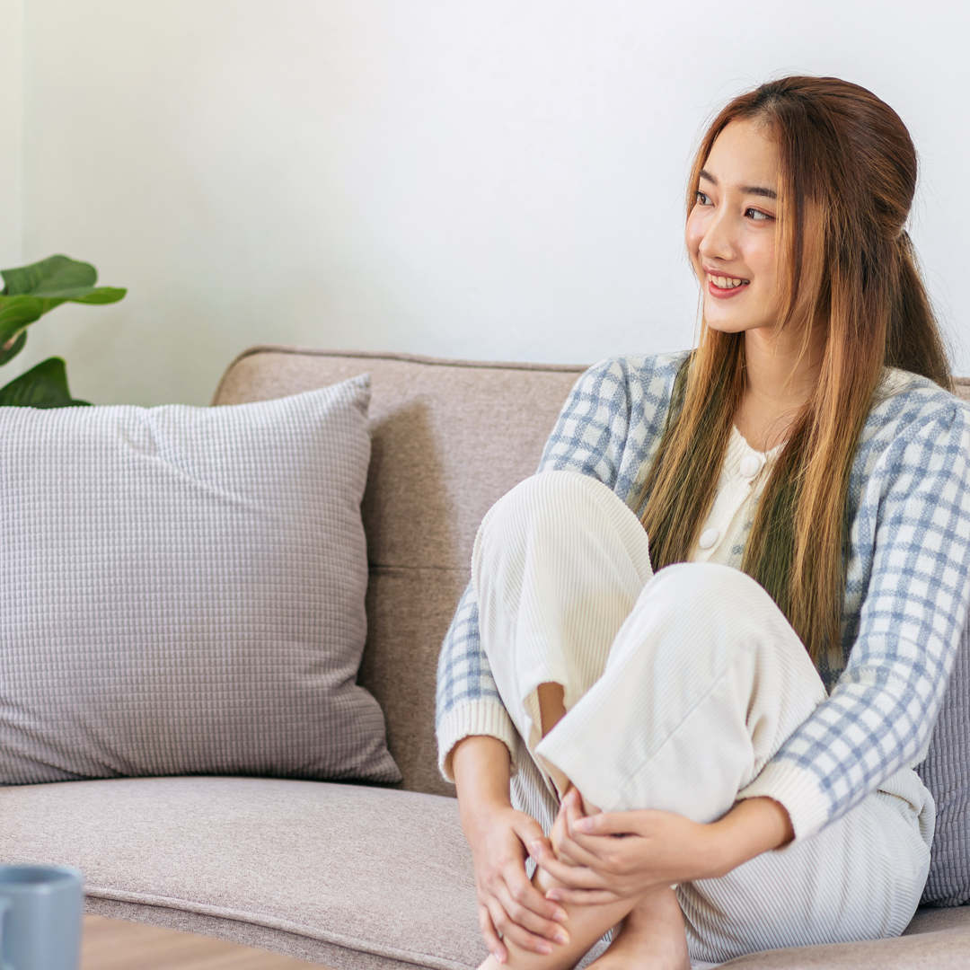 A woman is sitting on a couch with her legs crossed