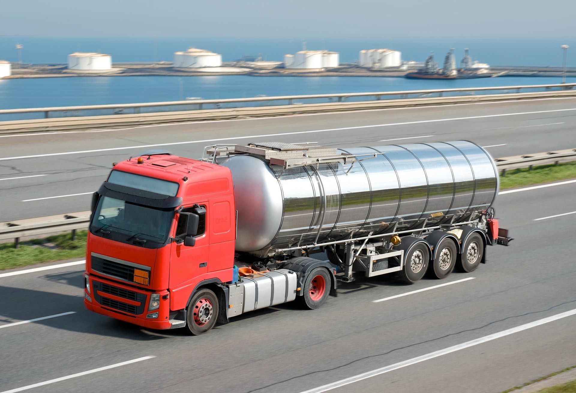 Red tanker truck delivering heating oil on a highway near a fuel storage terminal. Red tanker truck delivering heating oil on a highway near a fuel storage terminal.
