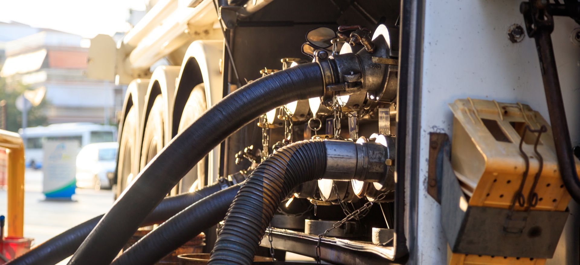 Close-up of industrial machinery with black hoses, metal fittings, and a beige control box