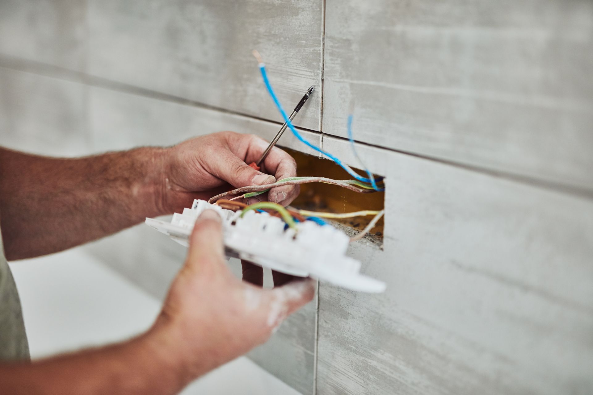 Electrician connecting wires to a wall outlet during installation. Electrician connecting wires to a wall outlet during installation.