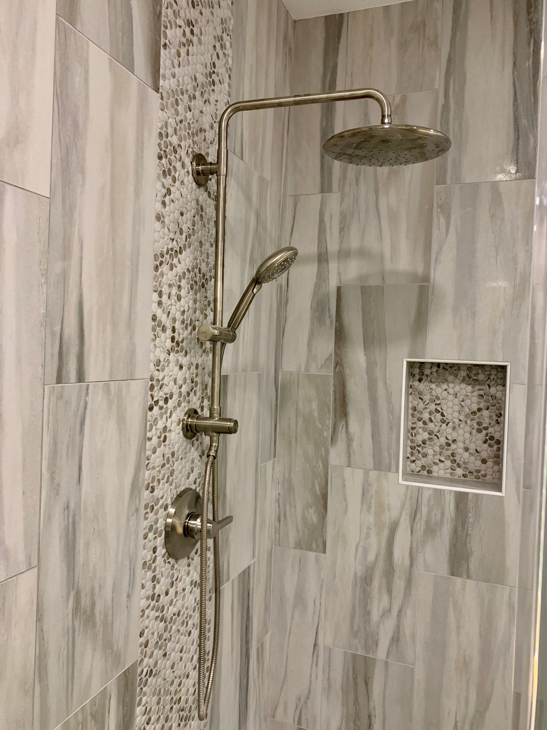 Shower with gray marble-look tile, rainfall showerhead, and a hand-held sprayer.