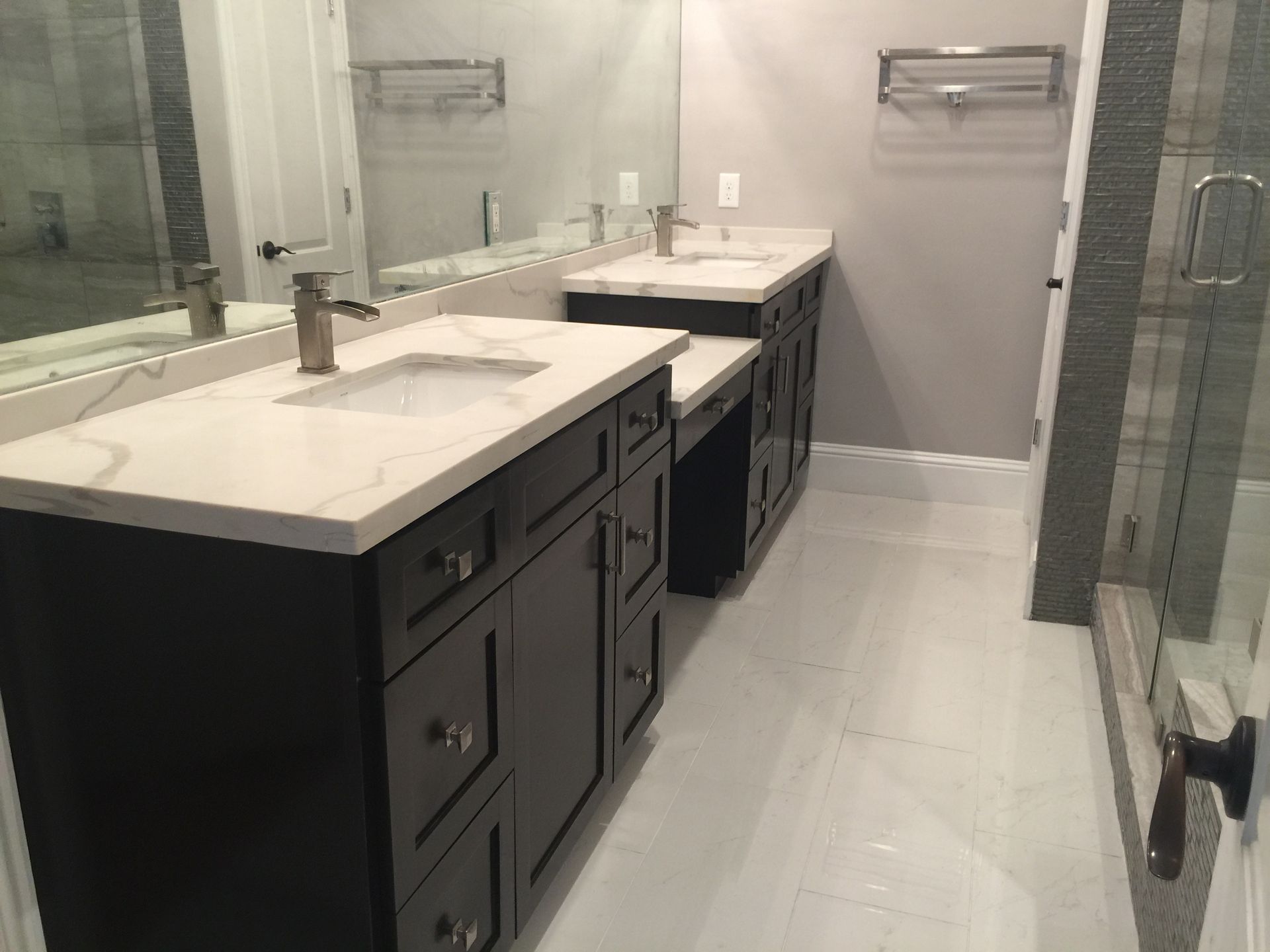 Bathroom with dark cabinets, white countertops, and two sinks. 