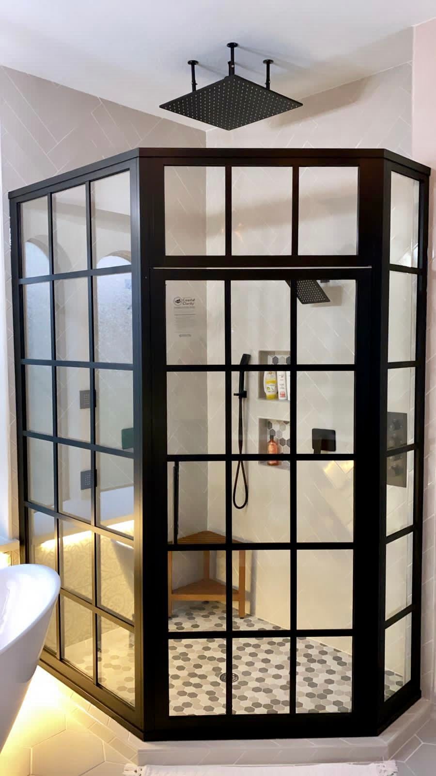 Black framed glass shower enclosure with square rain shower head.