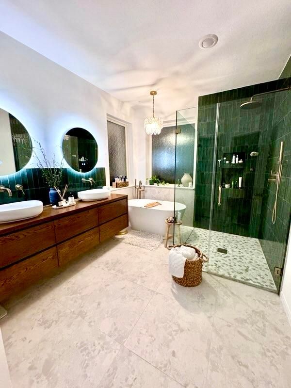 Modern bathroom with a wooden vanity, round mirrors, a green tiled shower, and a freestanding bathtub.