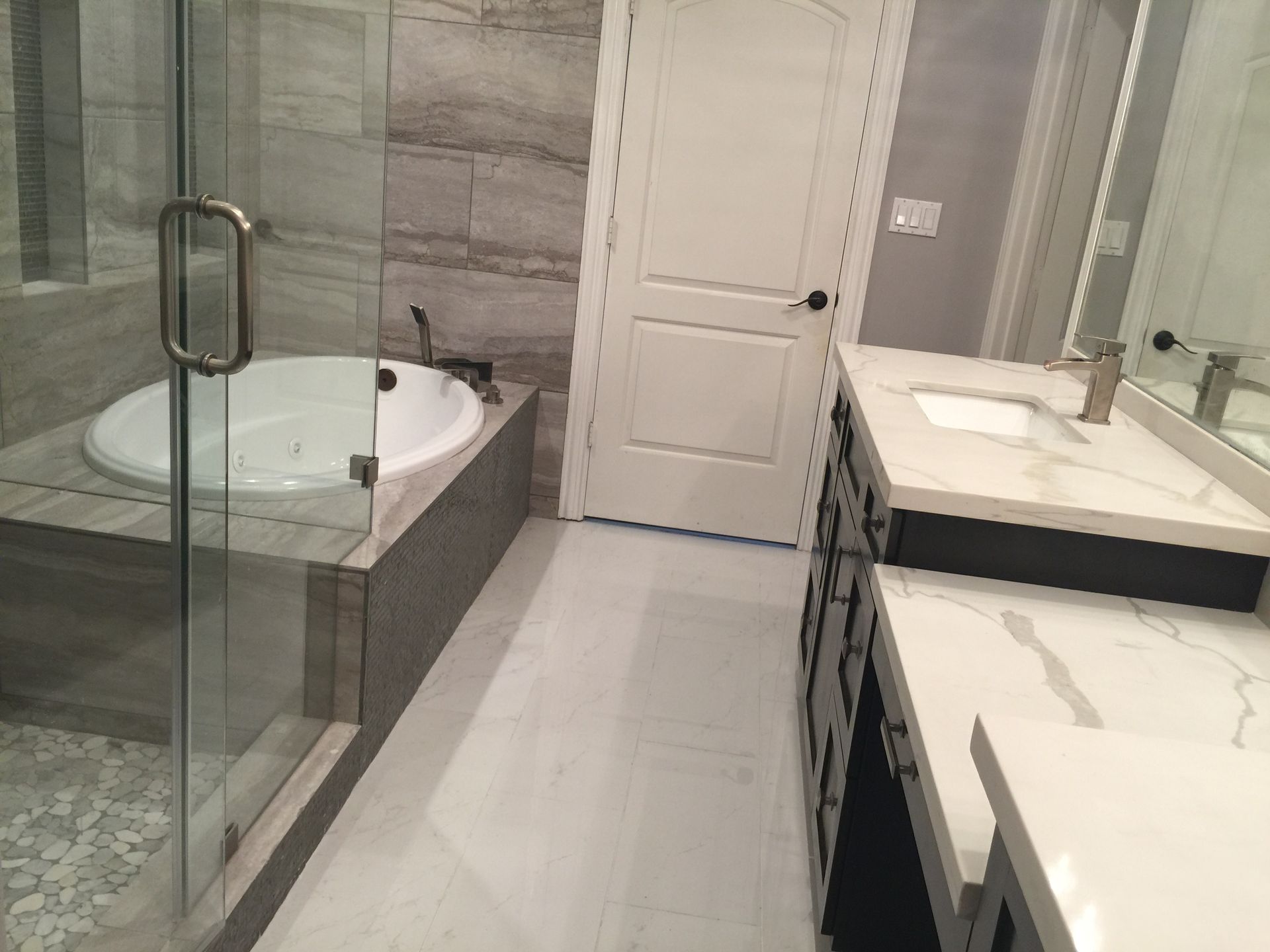 Modern bathroom with a glass shower, soaking tub, and vanity with white countertops.